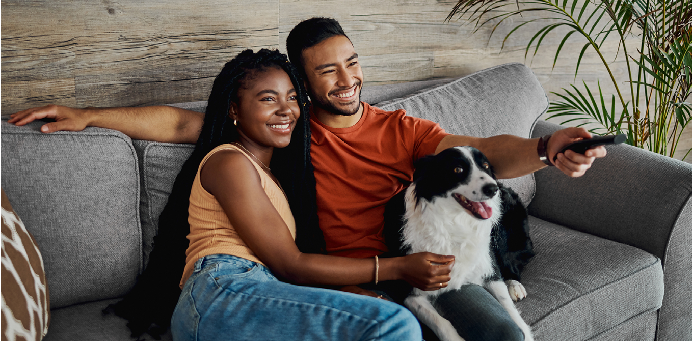 a couple on the couch with their dog